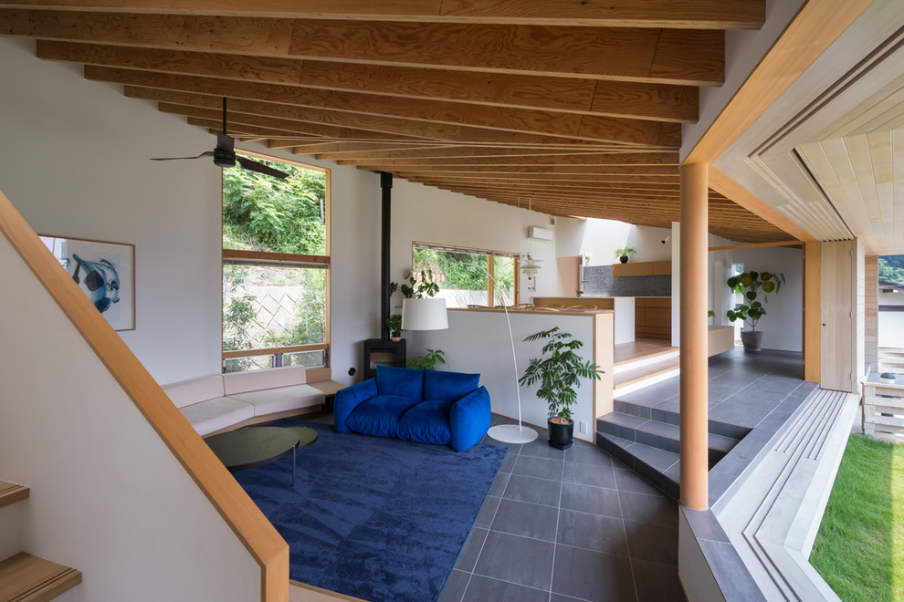 Пример оригинального дизайна: открытая гостиная комната в стиле модернизм с белыми стенами, полом из керамогранита и печью-буржуйкой