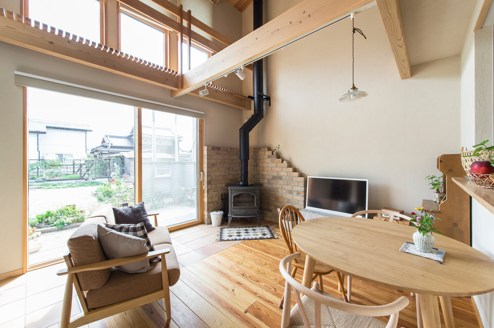 Réalisation d'un salon champêtre de taille moyenne et ouvert avec un mur blanc, un sol en bois brun, un poêle à bois, un manteau de cheminée en carrelage et un téléviseur indépendant.