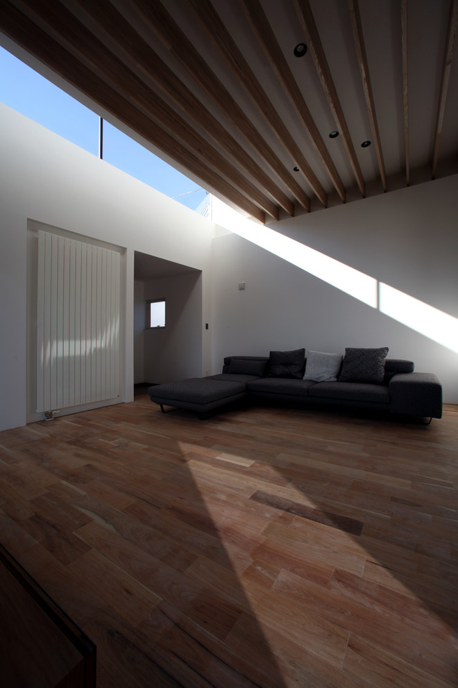 Offenes Modernes Wohnzimmer mit weißer Wandfarbe und braunem Holzboden