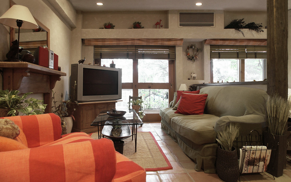 Foto på ett lantligt vardagsrum, med vita väggar, klinkergolv i terrakotta, en fristående TV och orange golv