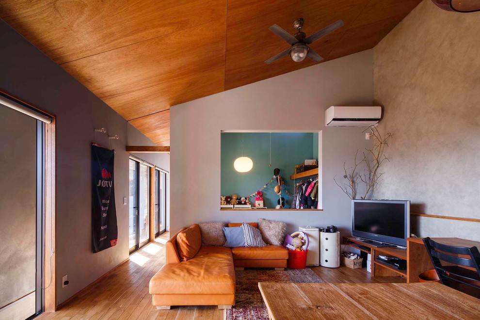Idee per un soggiorno etnico di medie dimensioni e aperto con pareti grigie, pavimento in legno massello medio, TV autoportante e pavimento marrone