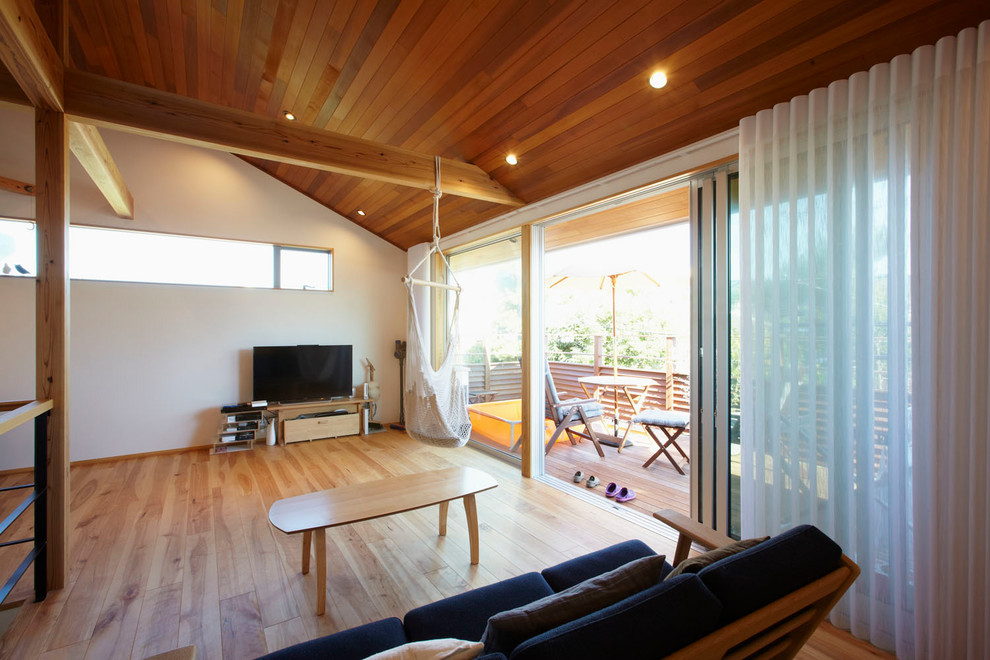 Foto di un soggiorno minimalista con pareti bianche, pavimento in legno massello medio, TV autoportante e pavimento marrone