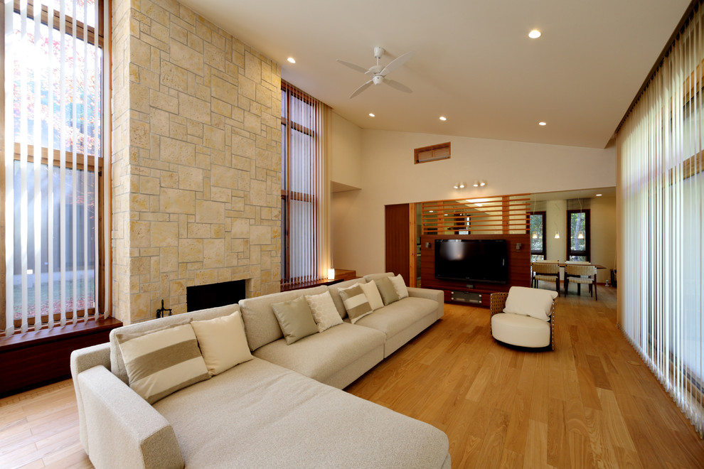 Large trendy formal and open concept light wood floor and beige floor living room photo in Other with white walls, a standard fireplace, a brick fireplace and a wall-mounted tv