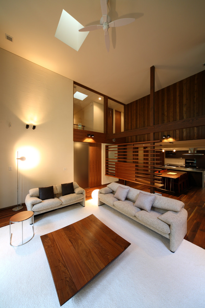 Idée de décoration pour un salon minimaliste de taille moyenne et ouvert avec une salle de réception, un mur blanc, parquet foncé, un téléviseur fixé au mur et un sol marron.