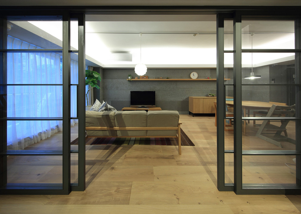 Offenes Asiatisches Wohnzimmer ohne Kamin mit Sperrholzboden, beigem Boden, grauer Wandfarbe und freistehendem TV in Tokio