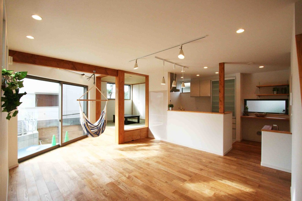 Idée de décoration pour un salon asiatique avec un mur blanc et un sol en bois brun.