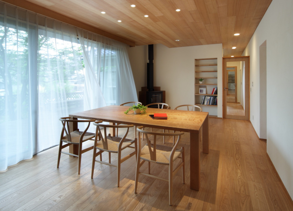 Exemple d'une salle à manger moderne de taille moyenne avec un mur blanc, parquet foncé, un poêle à bois, un manteau de cheminée en carrelage, un sol marron et un plafond en bois.