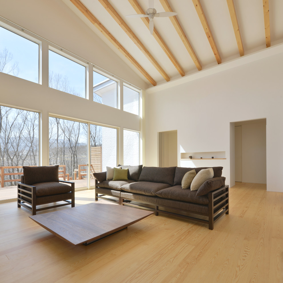 Diseño de salón blanco asiático con paredes blancas, suelo de madera clara y suelo marrón