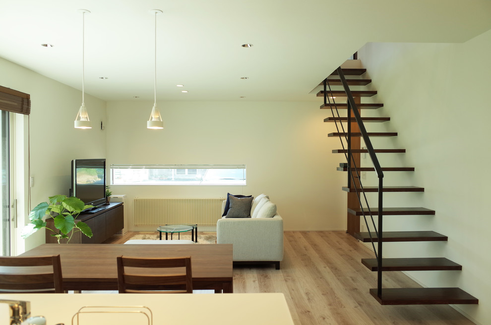 Idée de décoration pour un salon minimaliste ouvert avec un mur blanc, parquet clair, un téléviseur indépendant et un sol marron.