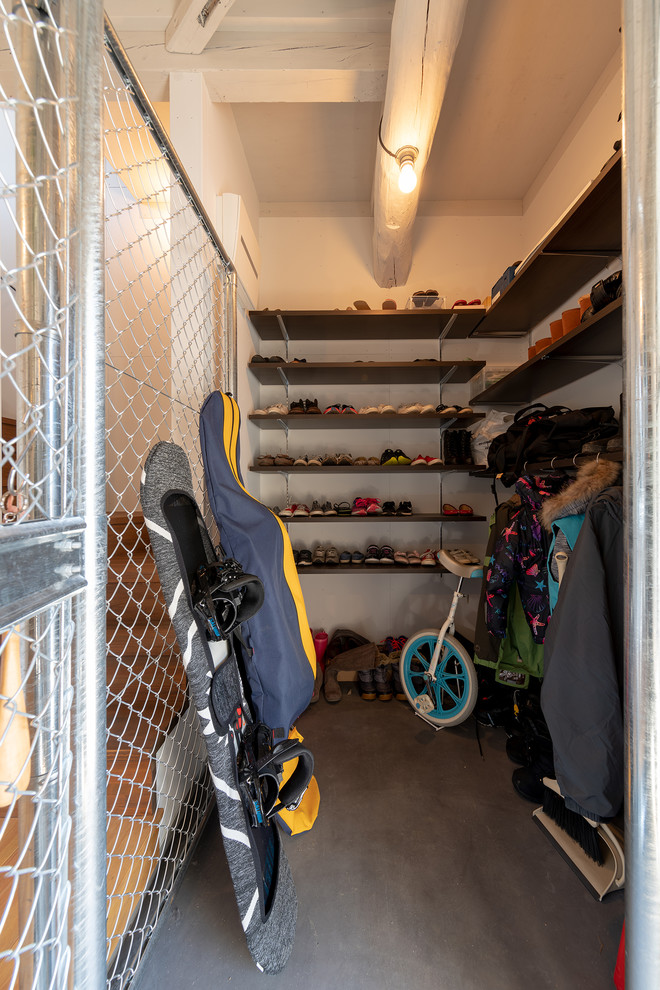 Diseño de armario vestidor unisex industrial con armarios abiertos, puertas de armario de madera en tonos medios, suelo de cemento y suelo gris