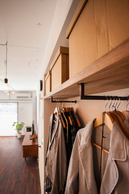 Ejemplo de armario de hombre minimalista pequeño con armarios abiertos, puertas de armario de madera oscura y suelo de madera oscura