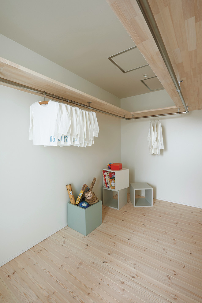 На фото: гардеробная комната в скандинавском стиле с светлым паркетным полом и бежевым полом