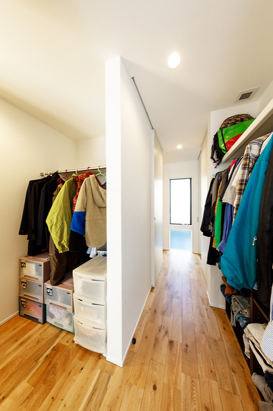 Foto på ett litet funkis walk-in-closet för könsneutrala, med öppna hyllor, vita skåp, mellanmörkt trägolv och brunt golv