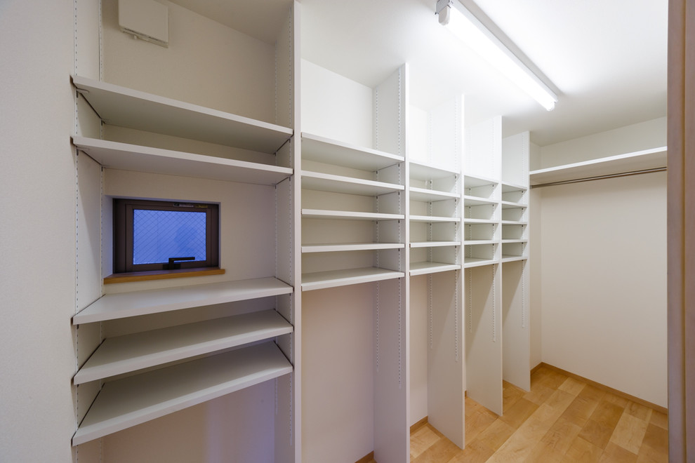 Ispirazione per una cabina armadio minimalista con pavimento in legno massello medio e pavimento beige