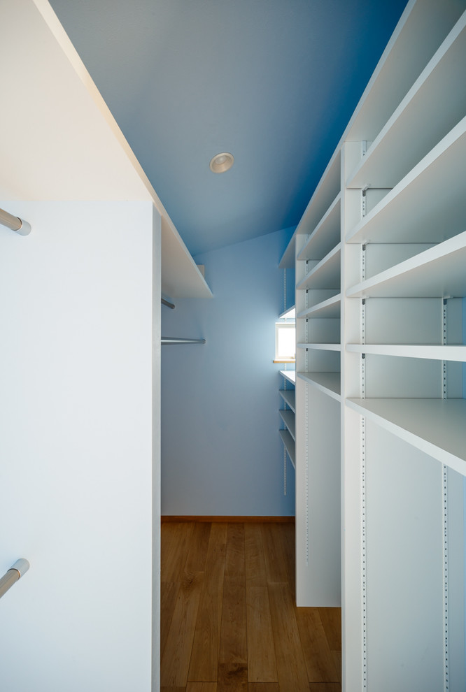 Foto di una cabina armadio minimalista con pavimento in legno massello medio e pavimento beige