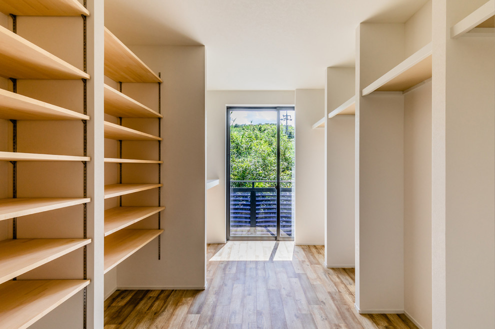 Ejemplo de armario vestidor unisex minimalista con armarios abiertos, suelo marrón y papel pintado
