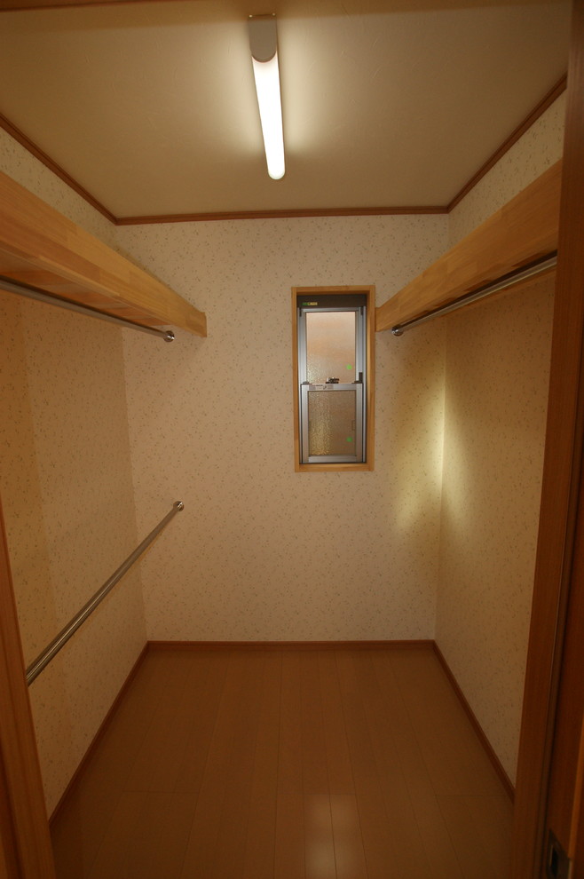 Ejemplo de armario y vestidor unisex con armarios con paneles lisos, puertas de armario de madera oscura y suelo de contrachapado