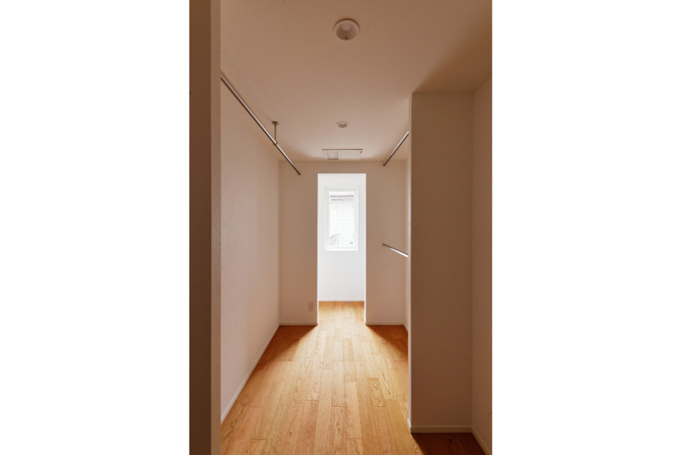 Cette image montre un dressing minimaliste avec un sol en contreplaqué et un plafond en papier peint.