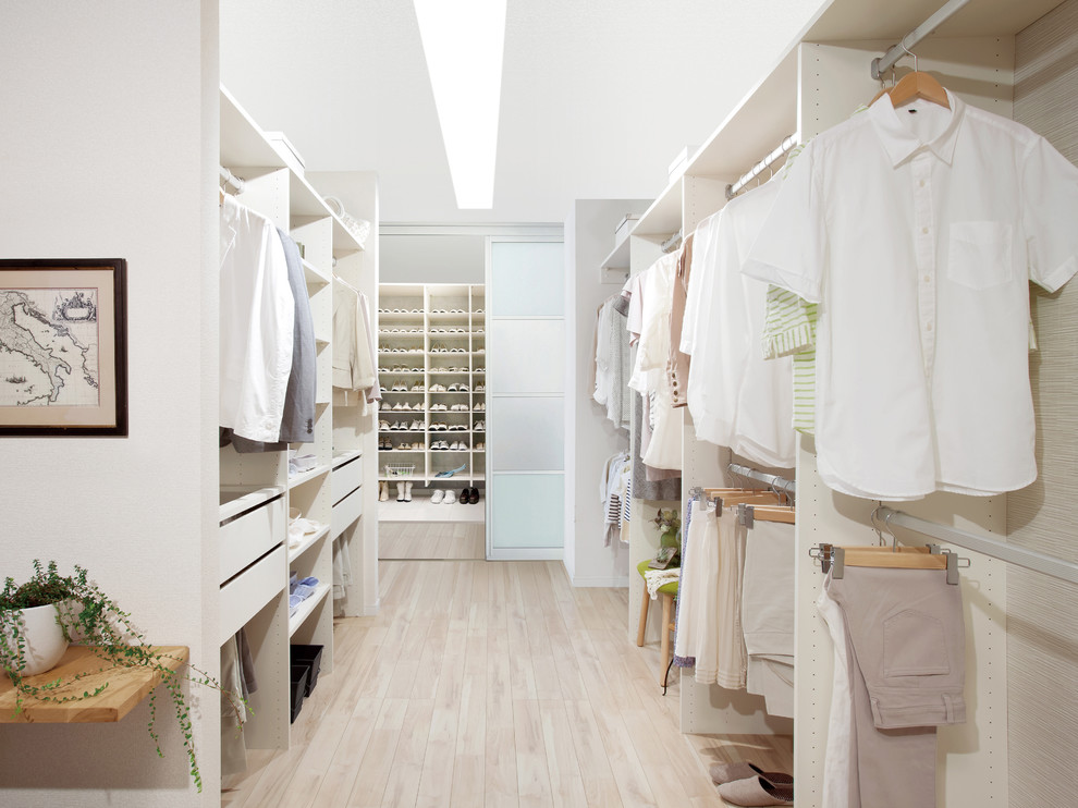 Diseño de armario vestidor unisex escandinavo grande con armarios abiertos, puertas de armario blancas, suelo de madera clara y suelo beige