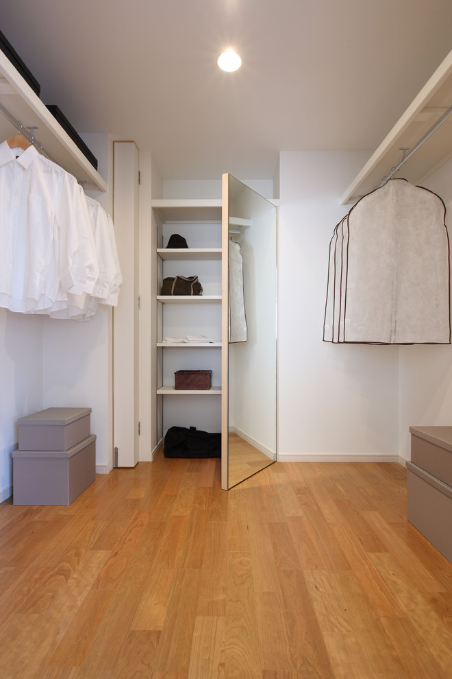 Inspiration för moderna walk-in-closets, med släta luckor, mellanmörkt trägolv och brunt golv