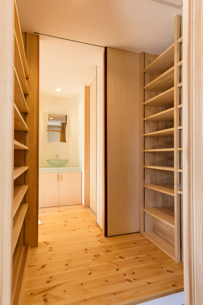 Foto di una piccola cabina armadio unisex con nessun'anta e pavimento in legno massello medio