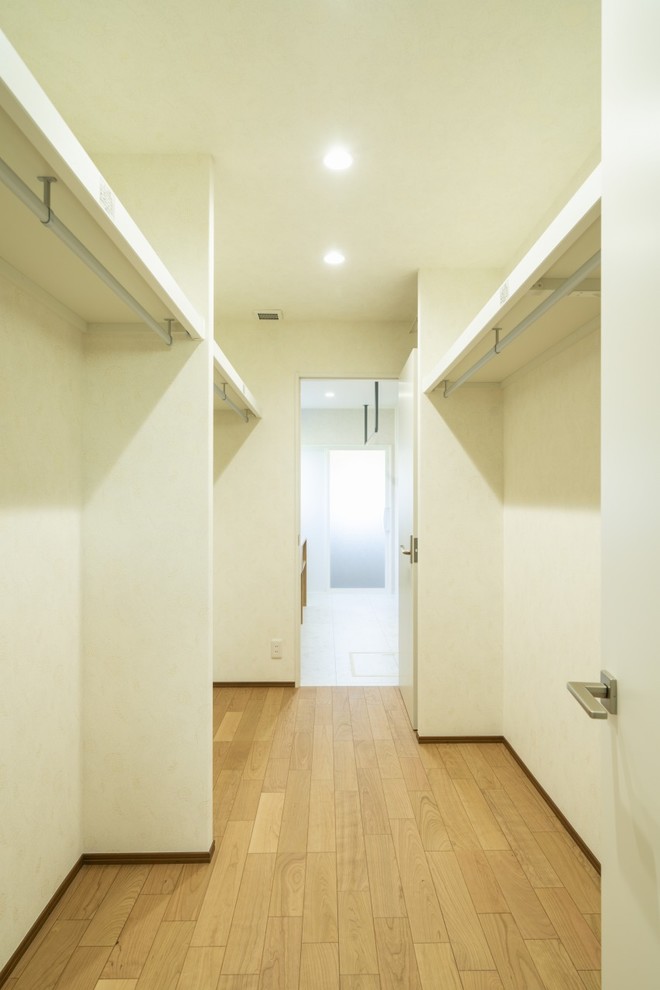 Diseño de armario vestidor unisex minimalista de tamaño medio con suelo de madera clara y suelo marrón