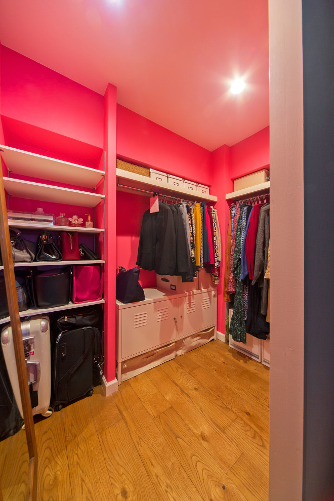 Foto på ett litet industriellt walk-in-closet för kvinnor, med mellanmörkt trägolv och brunt golv