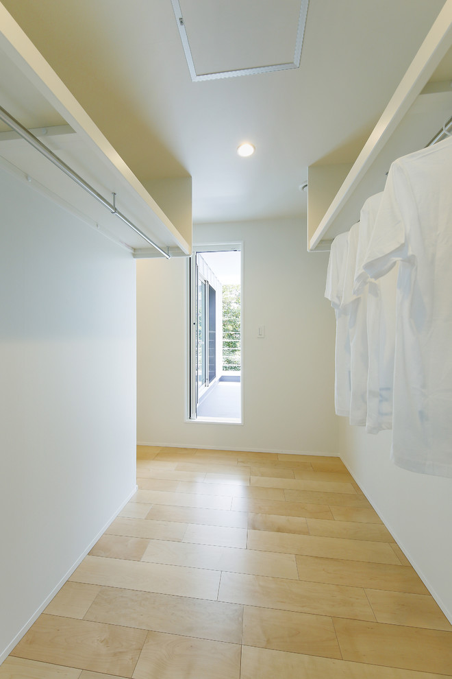 Modelo de armario vestidor unisex nórdico pequeño con armarios abiertos, puertas de armario blancas, suelo de madera clara, suelo marrón y papel pintado