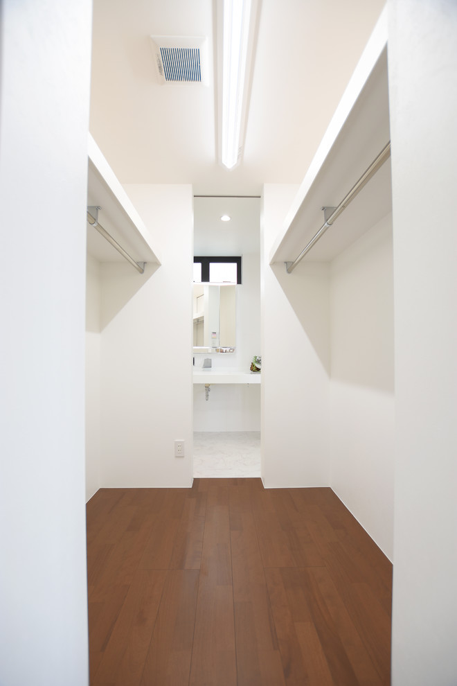 Imagen de armario vestidor unisex moderno con suelo de contrachapado y suelo marrón