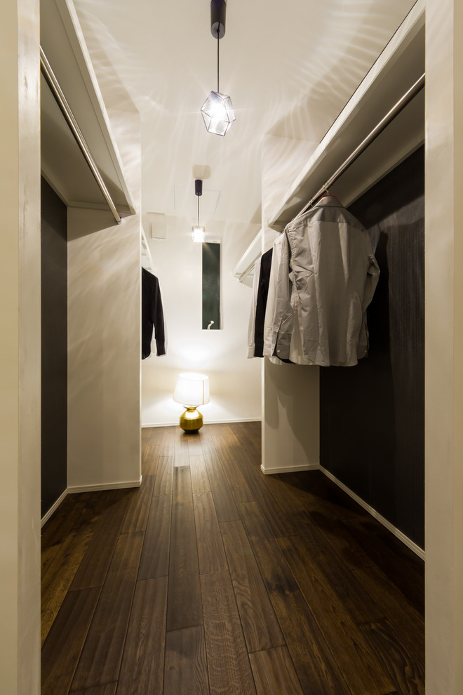 Trendy dark wood floor and brown floor walk-in closet photo in Other