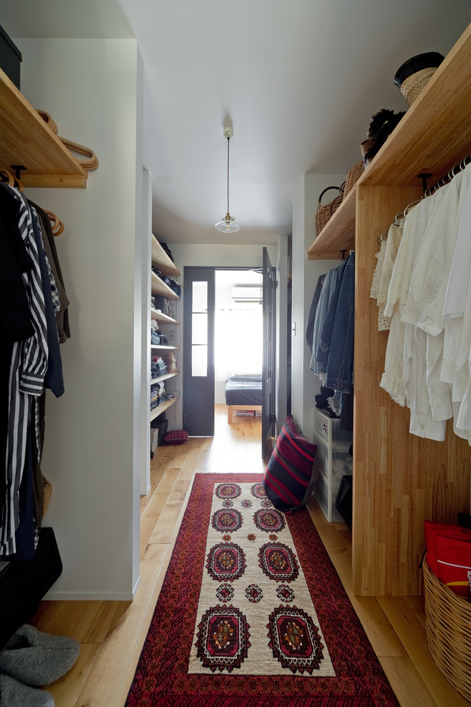 Ejemplo de armario vestidor unisex actual de tamaño medio con armarios abiertos, puertas de armario de madera oscura y suelo de madera en tonos medios