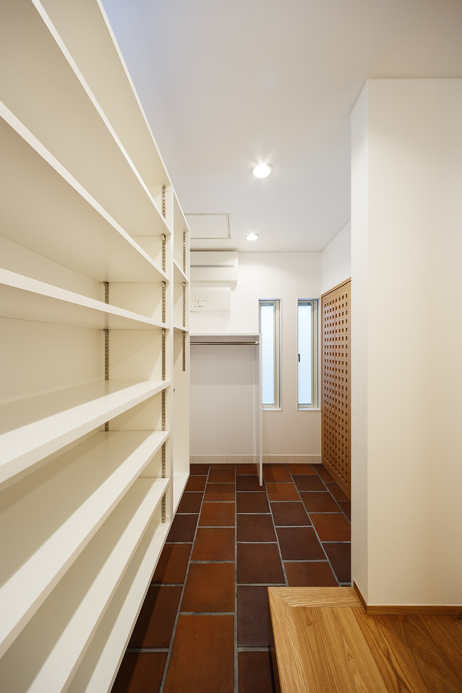 Modelo de armario vestidor unisex minimalista grande con armarios abiertos, puertas de armario blancas, suelo de baldosas de cerámica y suelo marrón
