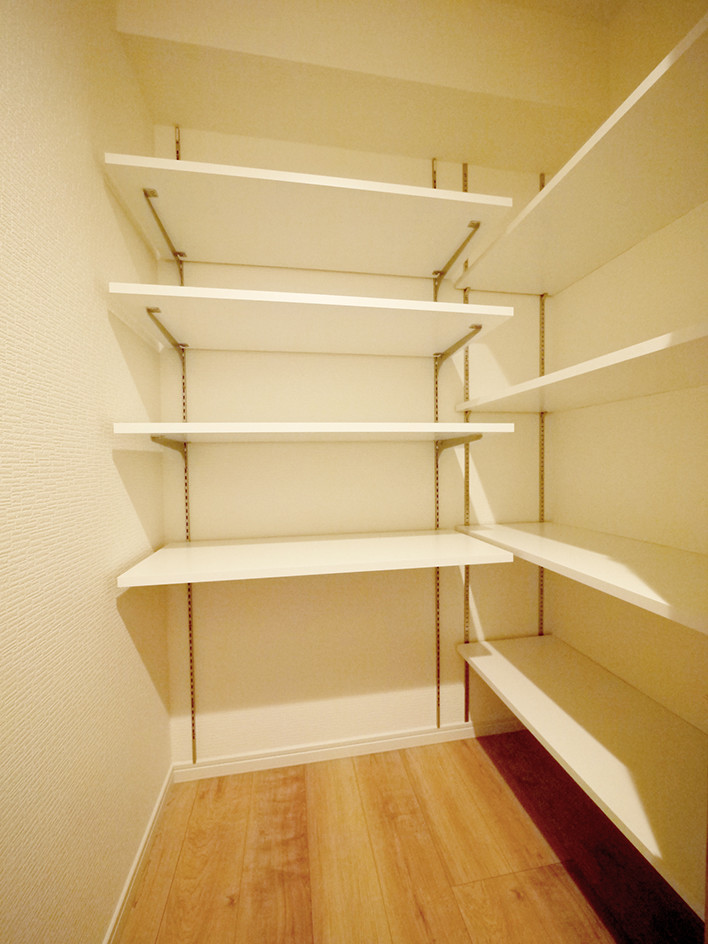 Example of a danish light wood floor and beige floor walk-in closet design in Tokyo with light wood cabinets