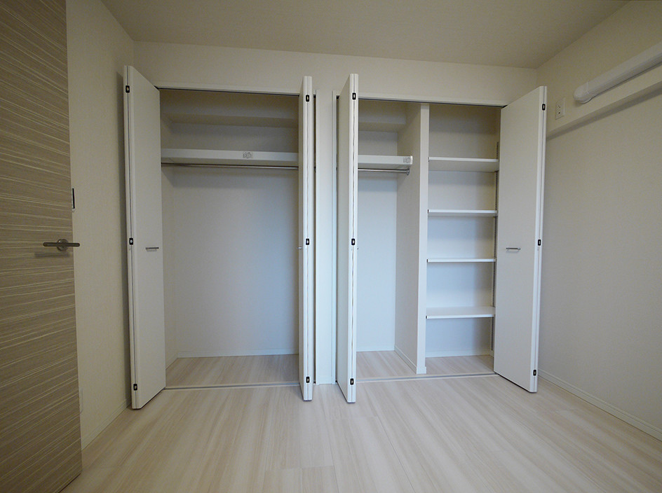Foto de armario y vestidor nórdico con puertas de armario blancas, suelo de contrachapado y suelo beige