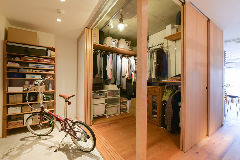 Immagine di una cabina armadio design con pavimento in legno massello medio e pavimento marrone
