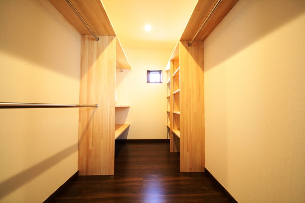 Ejemplo de armario vestidor unisex moderno con armarios abiertos, puertas de armario de madera oscura y suelo de madera oscura