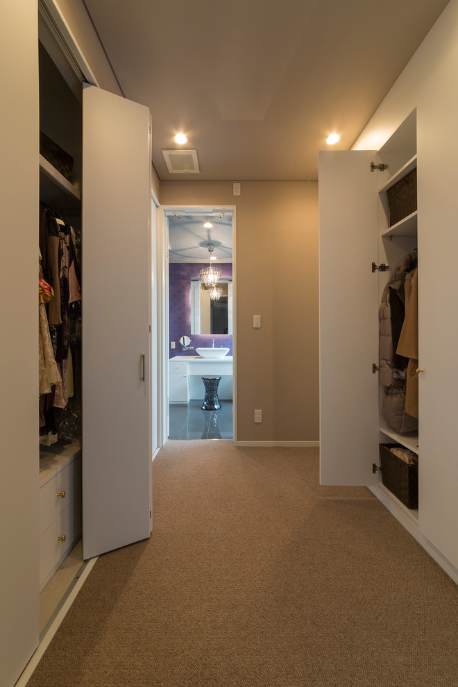 Neutrales Modernes Ankleidezimmer mit Ankleidebereich, flächenbündigen Schrankfronten, weißen Schränken und Teppichboden in Sonstige