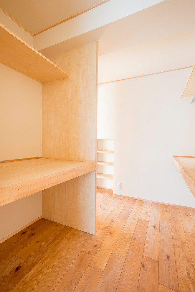 Ispirazione per una cabina armadio unisex moderna di medie dimensioni con pavimento in legno massello medio e pavimento beige