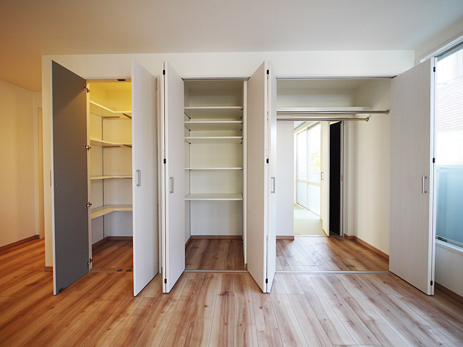 Idee per una cabina armadio mediterranea con pavimento in legno massello medio, pavimento marrone e ante bianche