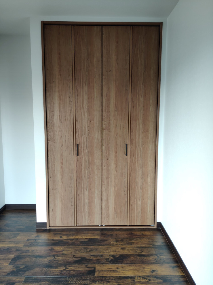 This is an example of a small modern gender neutral standard wardrobe in Other with flat-panel cabinets, dark wood cabinets, vinyl flooring, brown floors and a wallpapered ceiling.