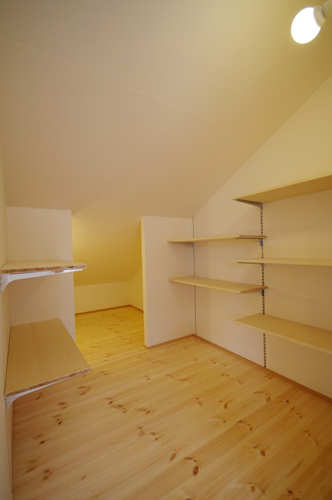 Imagen de armario vestidor unisex nórdico de tamaño medio con armarios abiertos, puertas de armario beige y suelo de madera clara
