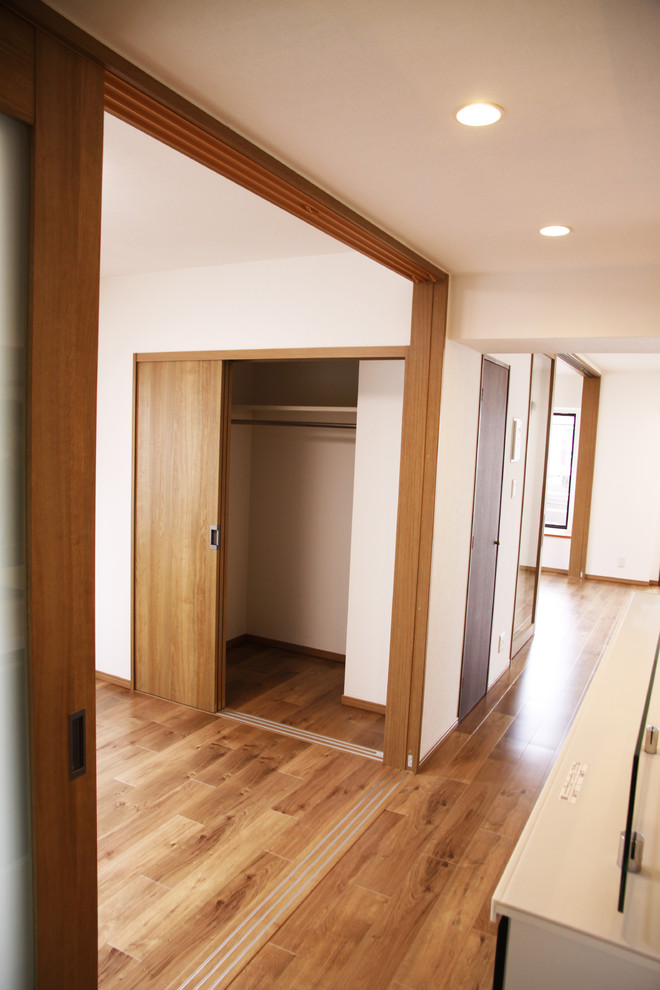 Modelo de armario vestidor escandinavo con puertas de armario de madera oscura y suelo de madera en tonos medios