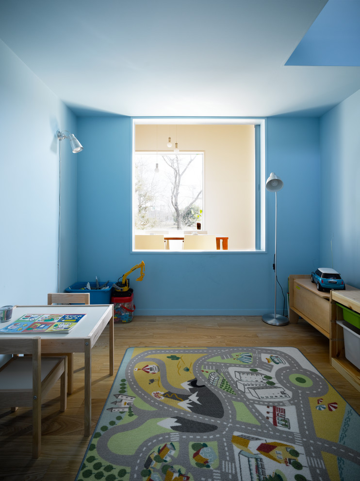 Imagen de dormitorio infantil de 4 a 10 años actual de tamaño medio con paredes azules, suelo marrón y suelo de contrachapado