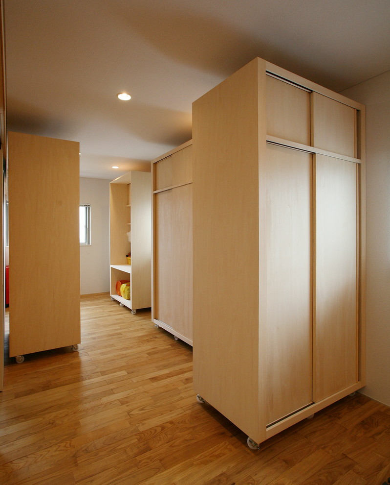 Cette image montre une chambre d'enfant asiatique avec un mur blanc et un sol en bois brun.