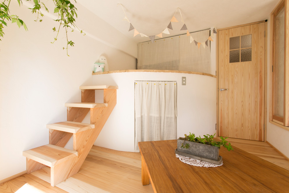 Diseño de dormitorio infantil de estilo zen con paredes blancas, suelo de madera clara y suelo marrón