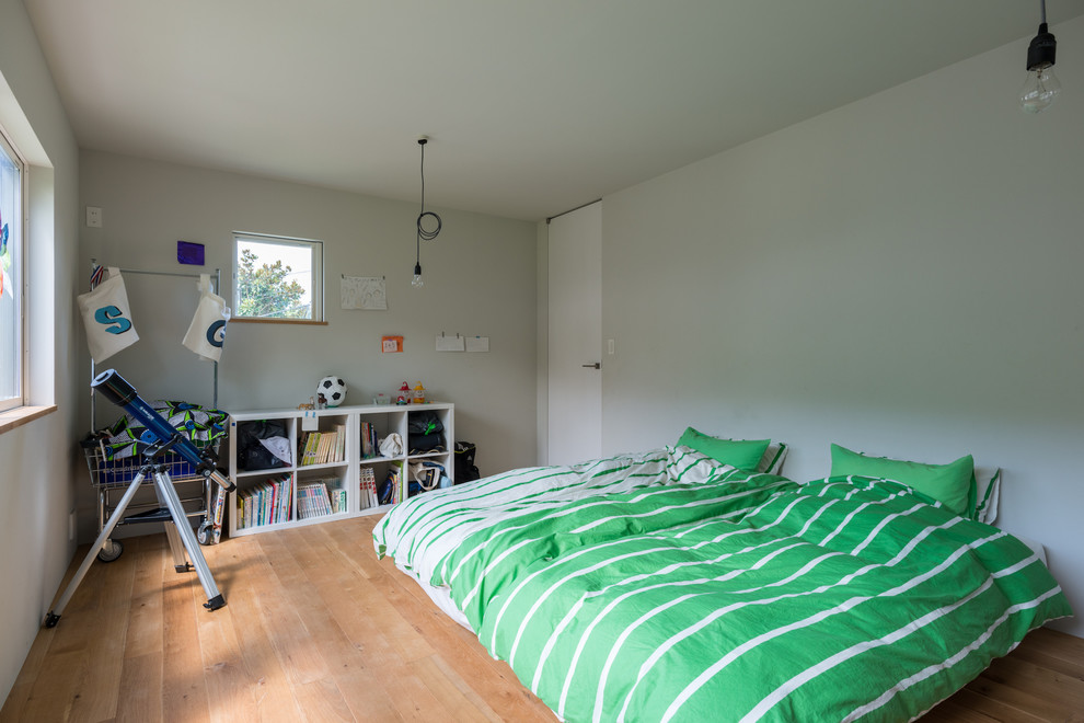 Ejemplo de dormitorio infantil actual con paredes azules, suelo de madera en tonos medios y suelo marrón
