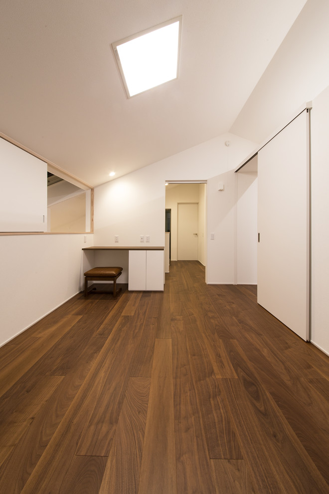 Bild på ett funkis barnrum kombinerat med sovrum, med vita väggar, plywoodgolv och brunt golv