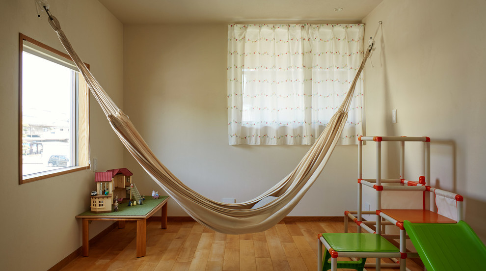 This is an example of a world-inspired gender neutral playroom in Other with beige walls, medium hardwood flooring and brown floors.