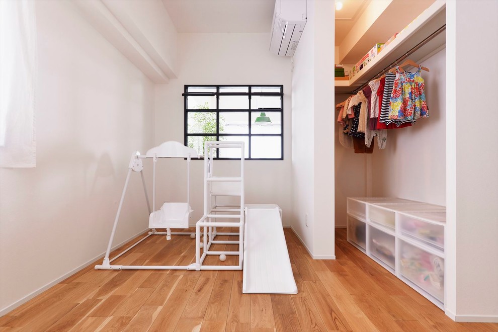 Foto på ett minimalistiskt barnrum, med vita väggar, mellanmörkt trägolv och brunt golv
