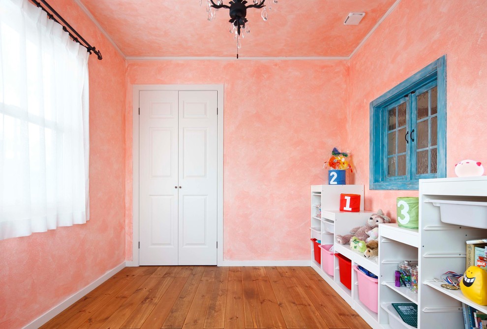 Modernes Kinderzimmer mit Spielecke, rosa Wandfarbe, braunem Holzboden und braunem Boden in Sonstige